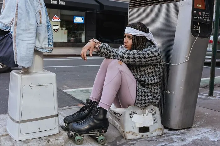 Young woman in roller skates sitting on a box on a NYC street, capturing powerful street moments in urban life.