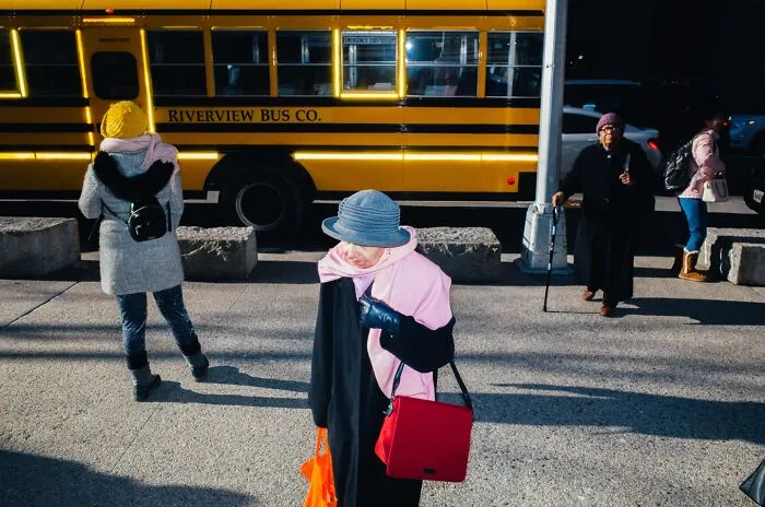 Elderly woman with bright accessories walking on a New York City street captured in a powerful street moment.