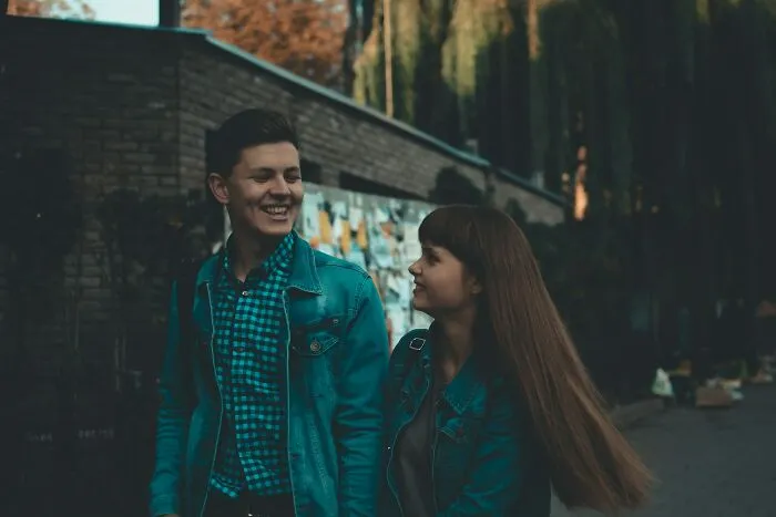 Two young people smiling and talking outdoors, illustrating interactions with pathological liars in casual setting.