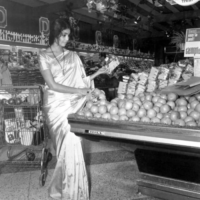 Woman Dressed In A Sari Examines Fruit In The Grocery Store, Tallahassee, Florida, 1971