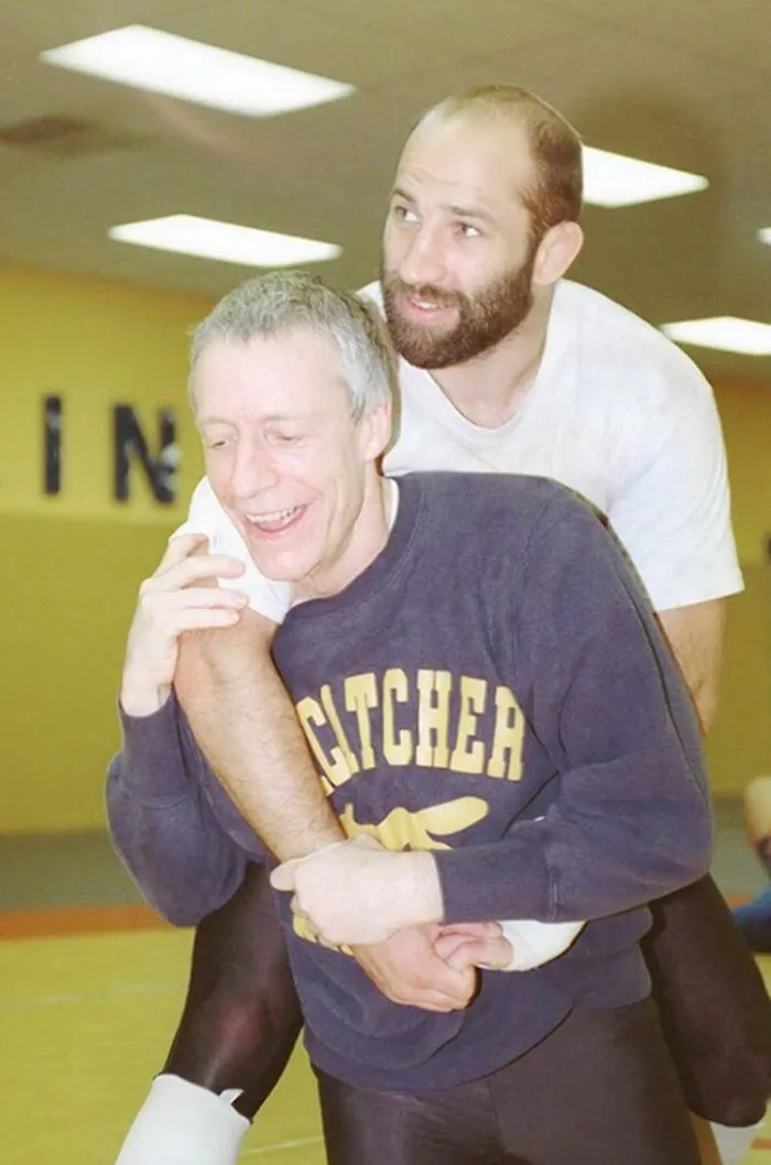 Two men practicing wrestling moves indoors, captured in a rare photo with a terrifying and horrific backstory.