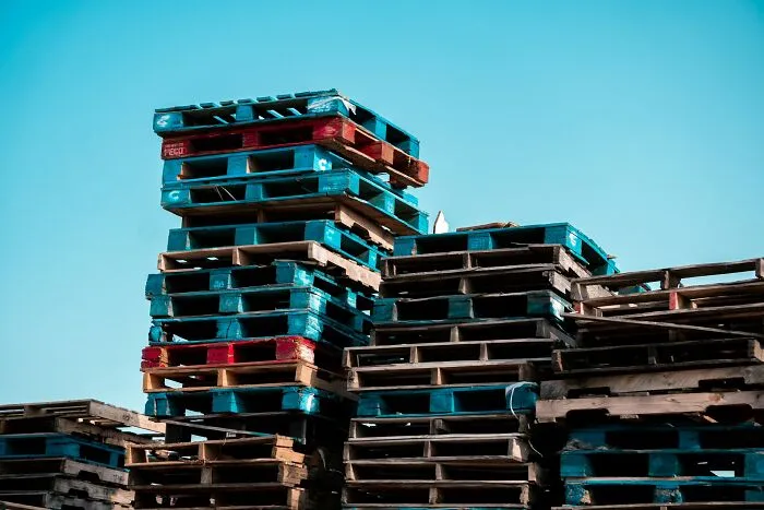Stacks of wooden pallets under clear blue sky representing arrogant people’s regret moments in conflict discussions.