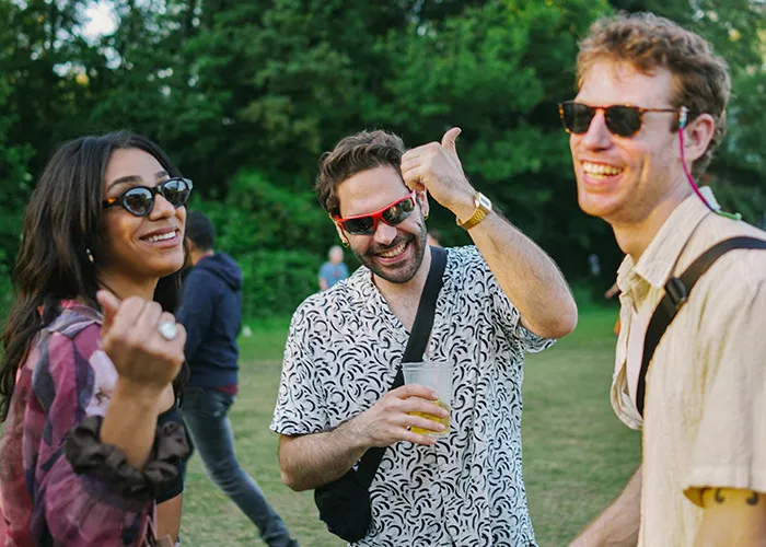 Three friends wearing sunglasses outdoors, smiling and enjoying a social gathering with doctors and health insights theme.