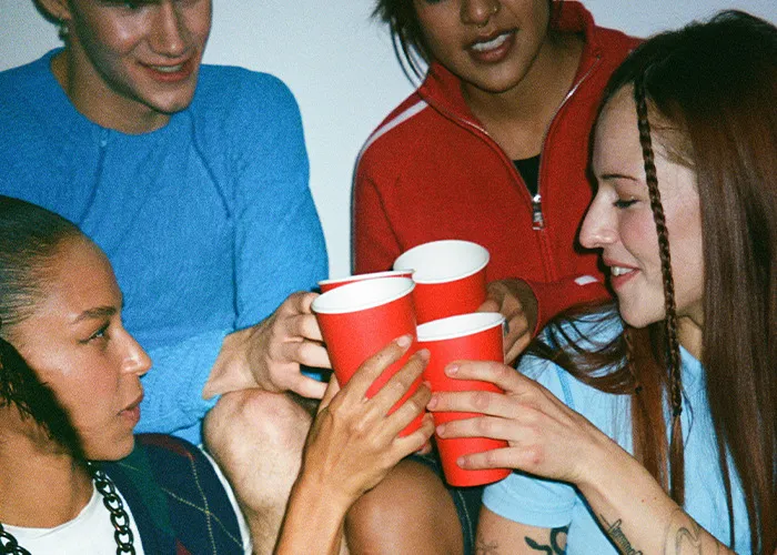 Group of young people holding red cups and toasting, illustrating dangers of death machines and health risks.
