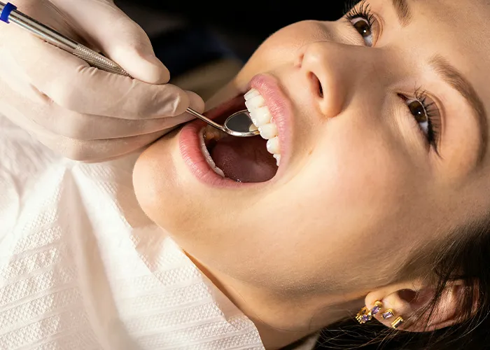 Close-up of a dentist using a dental mirror to examine the mouth of a patient at a medical clinic.