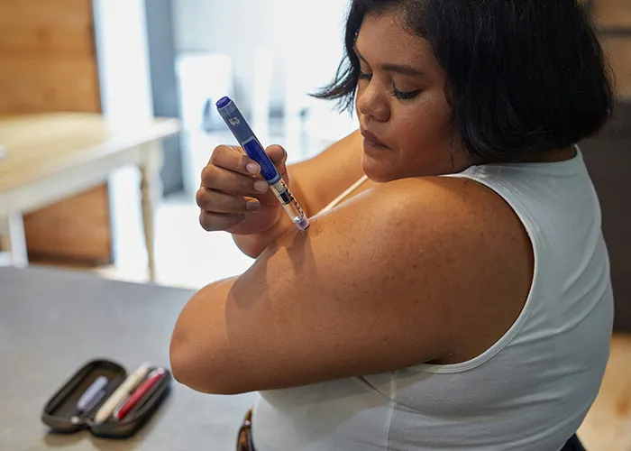 Woman injecting insulin into her arm, illustrating concerns doctors share about death machines like medical devices.