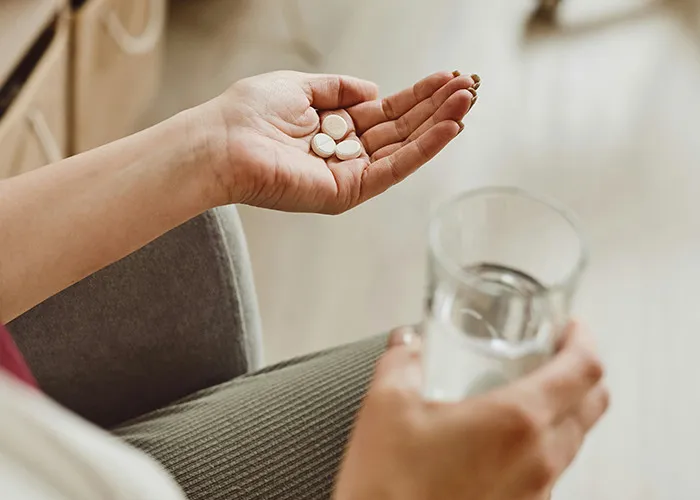 Hand holding pills and a glass of water highlighting doctors' warnings about death machines in healthcare settings.