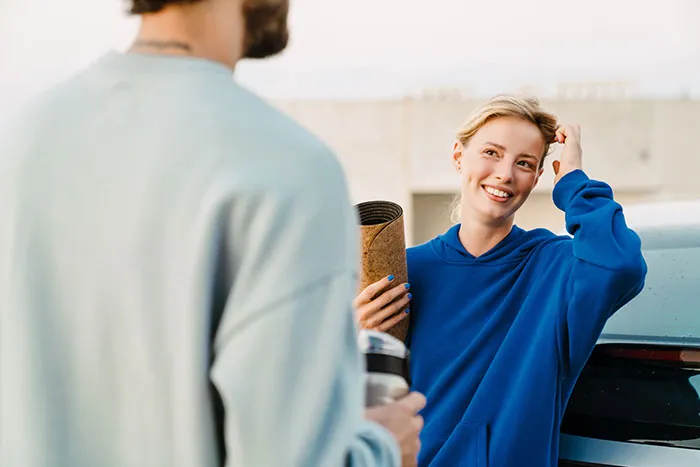 Young woman in a blue hoodie smiling and talking with a man, illustrating single male behaviors that destroy romance hope.