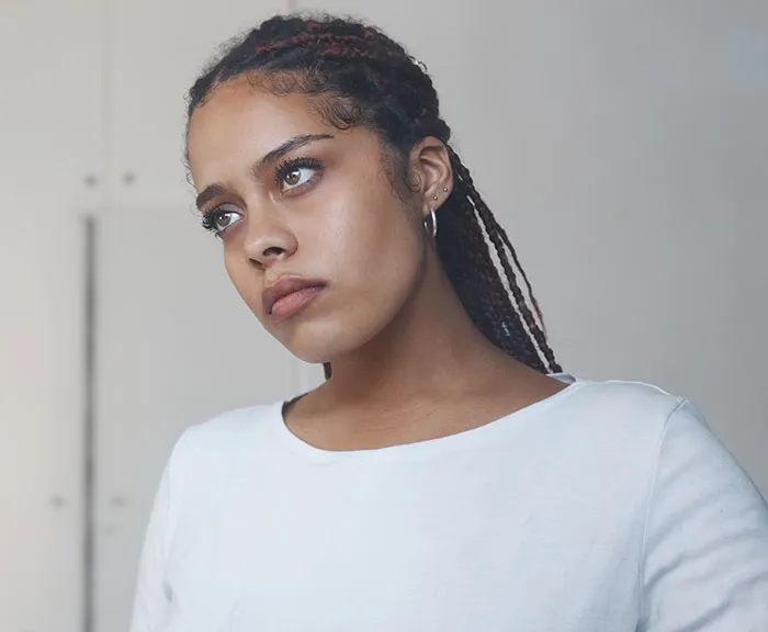 Young woman with braided hair looking thoughtful, reflecting on single male behaviors that affect romance prospects.