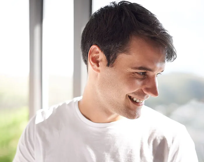 Young single male smiling and looking down, illustrating common single male behaviors affecting romance chances.