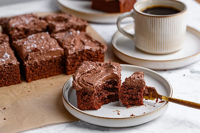 Chocolate frosted brownies on a plate with coffee, showcasing popular cooking secrets and ingredients for rich flavor.