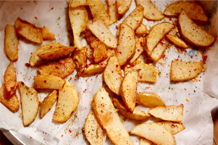 Seasoned potato wedges on parchment paper showcasing cooking secrets and unique ingredients for crispy results.