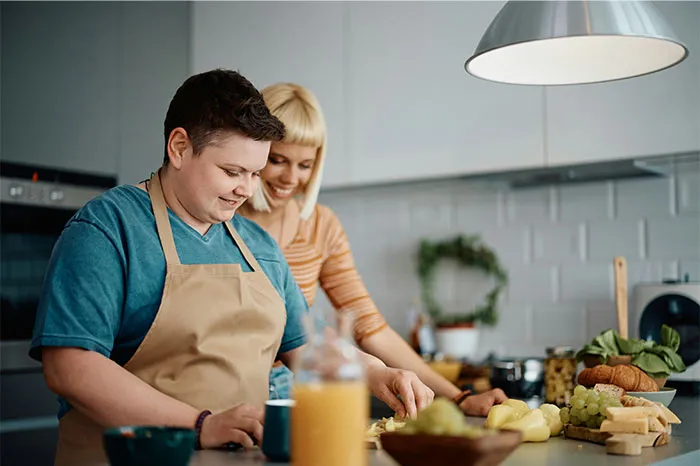 Two people cooking together in a modern kitchen, sharing cooking secrets and unique ingredients while preparing food.