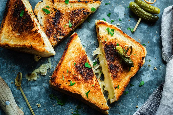 Grilled cheese sandwich with melted cheese and fresh herbs, showcasing cooking secrets and unique ingredients.