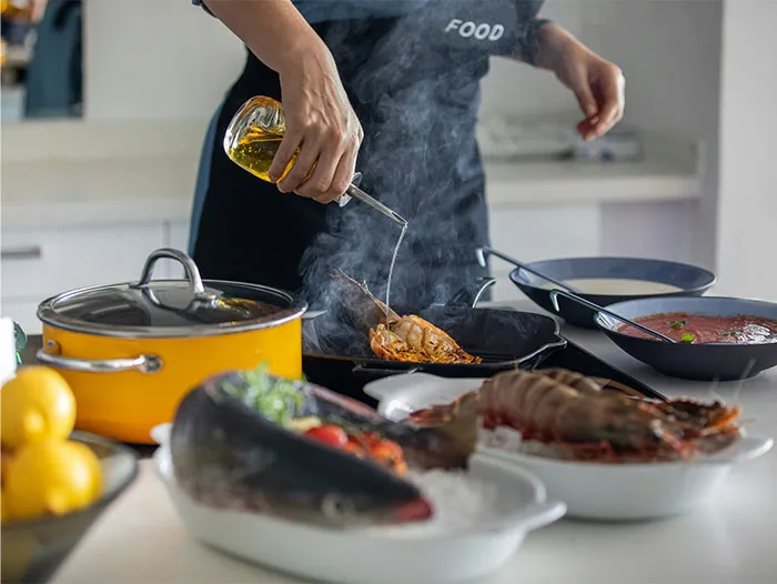 Person pouring oil while cooking seafood, illustrating cooking secrets and ingredients shared by home chefs.