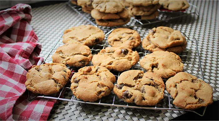 Freshly baked chocolate chip cookies cooling on a rack, illustrating cooking secrets and unique ingredients shared.