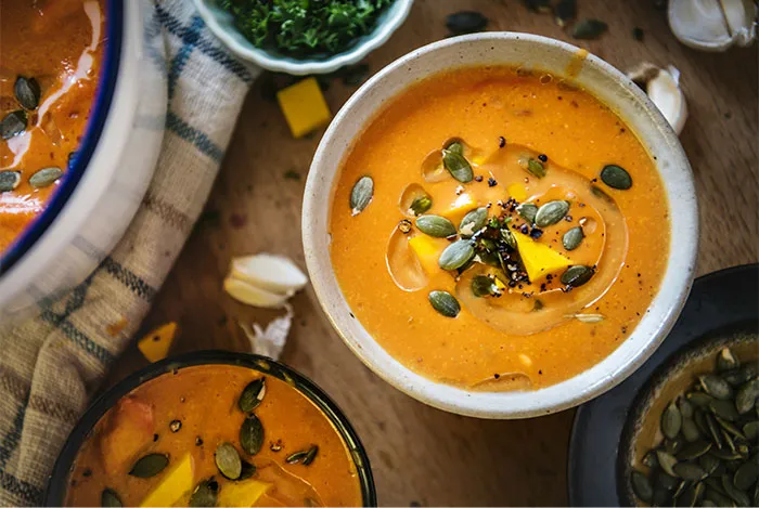 Creamy pumpkin soup garnished with seeds and herbs, showcasing cooking secrets and unique ingredients revealed by people.