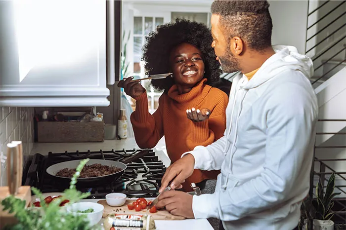Couple sharing cooking secrets in a modern kitchen, preparing ingredients and enjoying the cooking process together.