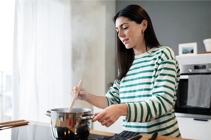 Woman cooking in a modern kitchen stirring a pot, sharing cooking secrets and ingredients for home recipes.