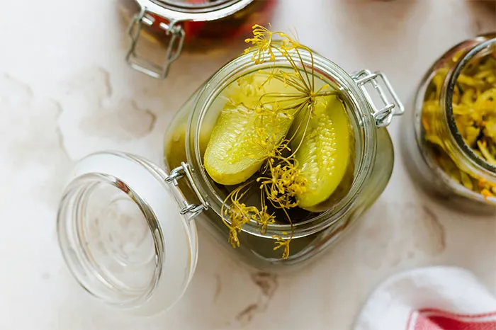 Glass jar with pickled cucumbers and dill, showcasing cooking secrets and unique ingredients in home recipes.