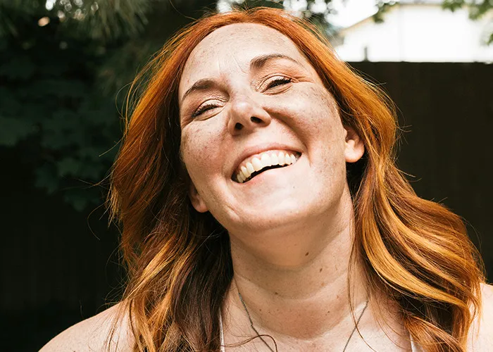 Red-haired woman smiling outdoors, conveying confidence and attitude related to savage insults shared by people.