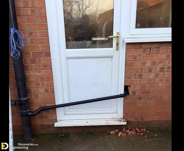 Pipe installed through a brick wall and a door, showcasing hilariously dumb engineering mistakes despite degrees.