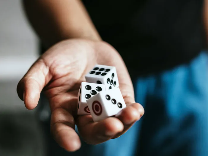 Hand holding three dice, symbolizing risk and chance related to unsafe neighborhoods and areas signs.