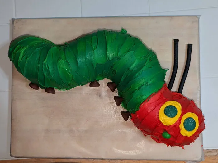 Brightly colored baked goods shaped like a caterpillar with green and red icing, showcasing creative baking skills.