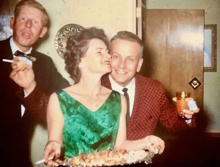 Candid glimpse into the past showing three people enjoying a party with drinks and appetizers in vintage attire.