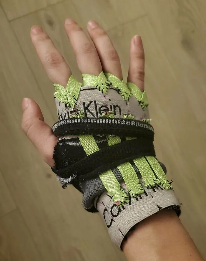 Hand wearing a homemade fingerless glove with green ribbon stitches, showcasing redneck engineering creativity and invention.