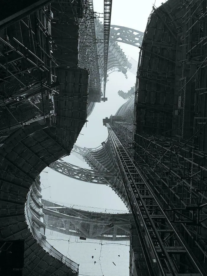 A low-angle view of extremely large, towering skyscrapers under construction, showing a scary and eerie perspective.