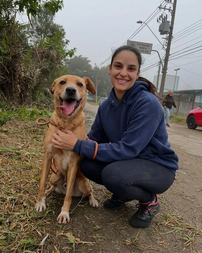 Young woman with shelter dog smiling happily during their weekly joyful walk outdoors on a foggy day.