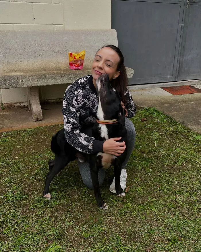 Woman crouching outdoors hugging a happy shelter dog, capturing the pure joy of shelter dogs on their weekly walks