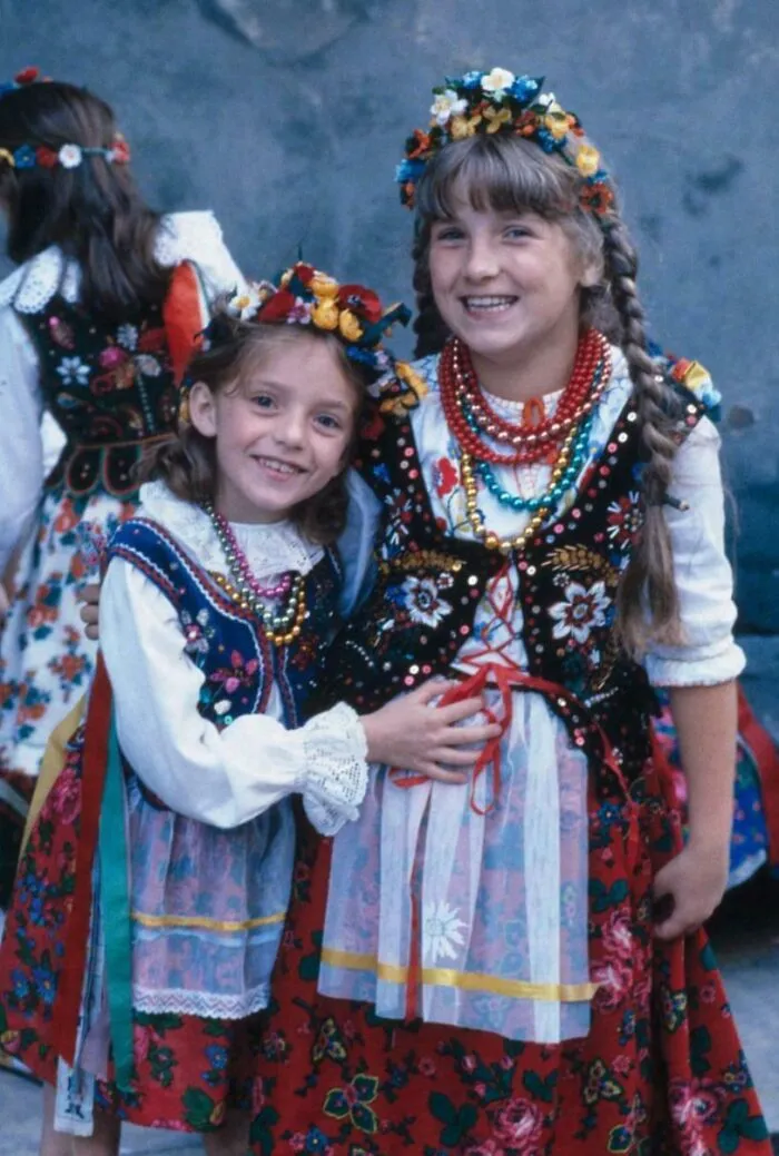 Dos chicas de Cracovia, Polonia, sonríen a la cámara vestidas con sus ropas tradicionales, 1983. Fotografía con Kodachrome.