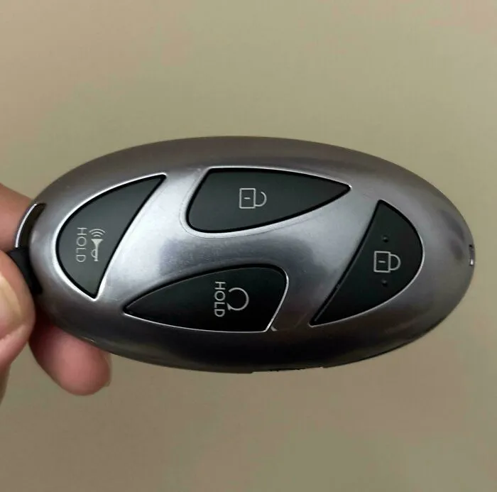 Sleek car key fob with smart button design held in hand, showcasing innovative and cool designer functionality.