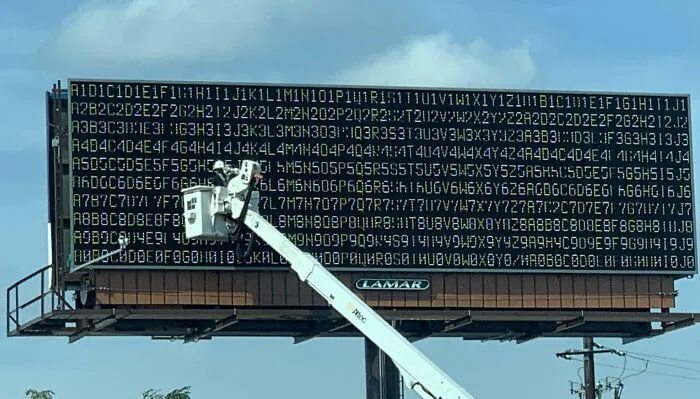 Cartel publicitario con error técnico que muestra caracteres y números ilegibles, ejemplo de fallos publicitarios divertidos.