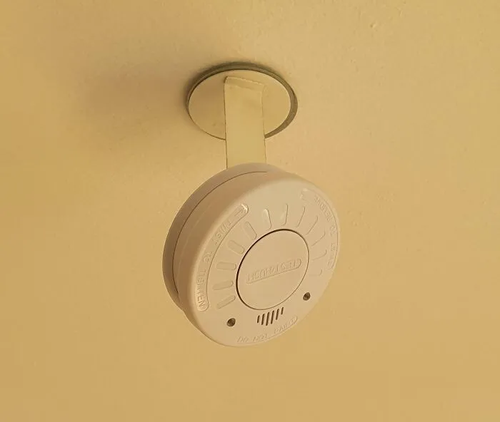 Detector de humo blanco instalado en techo con consecuencias visibles tras olas de calor veraniegas en la vivienda.