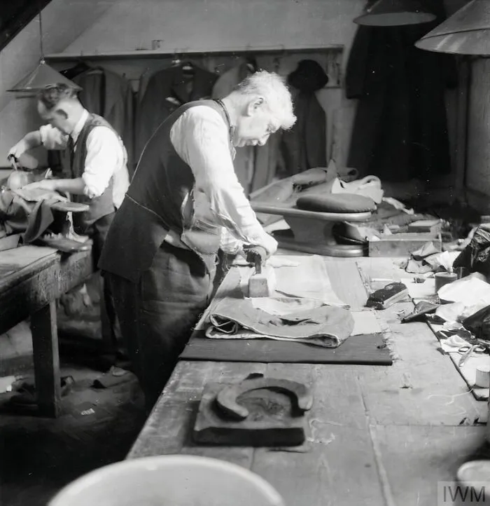 A Tailor Uses His 'Goose' (A Heavy Iron) To Press The Seams Of A Pair Of Trousers In The Workroom Of Henry Poole And Co. On Savile Row In London