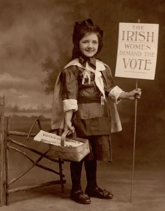 A Young Girl Holds Up A Sign Reading "The Irish Women Demand The Vote", Circa 1900s