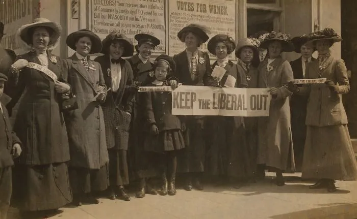 Group Of Women Suffragists Holding A Banner Saying 'Keep The Liberal Out' And Standing In Front Of Posters Explaining Their Opposition To Asquith In The Election