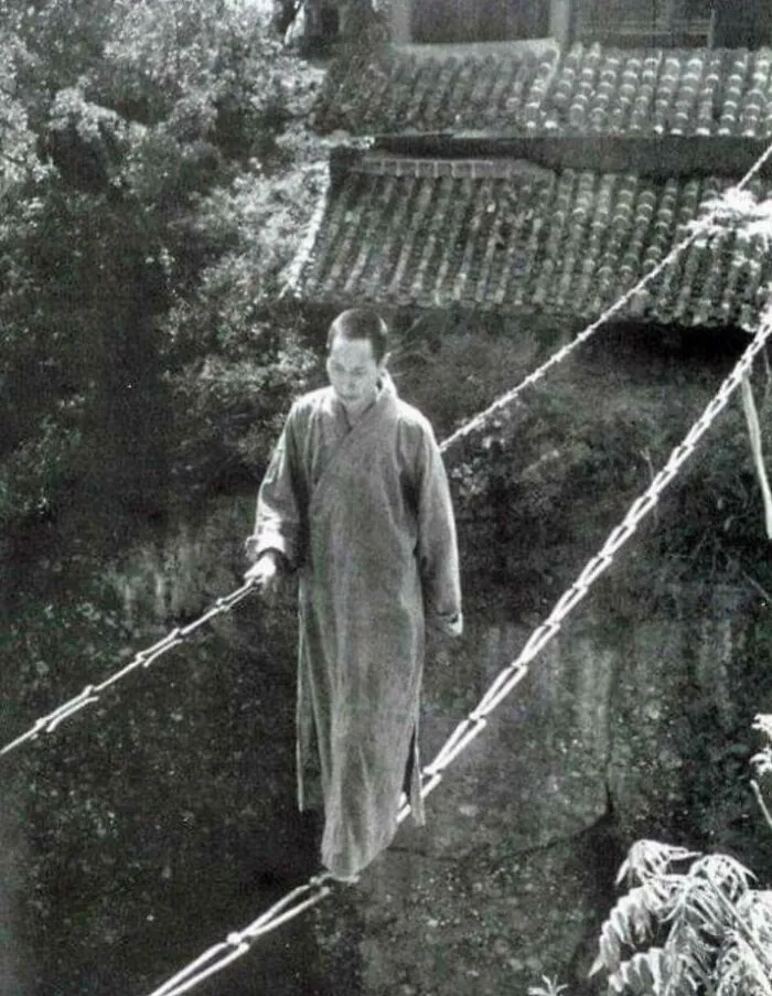 Monk Crossing A Chain Bridge At Yunyan Si In China