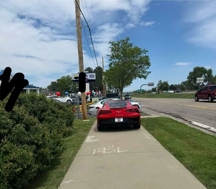 Coche deportivo rojo estacionado sobre la acera bloqueando el paso, ejemplo de personas prepotentes en internet.
