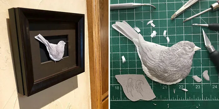 Paper wildlife sculpture of a bird with detailed feathers displayed in a black frame and crafted on a cutting mat.