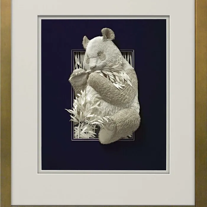 Realistic wildlife sculpture of a panda eating bamboo, intricately crafted from simple paper by an artist.