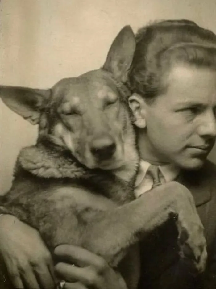 Vintage black and white photo of a man holding a relaxed dog, showcasing a historical perspective on pets and their bond.