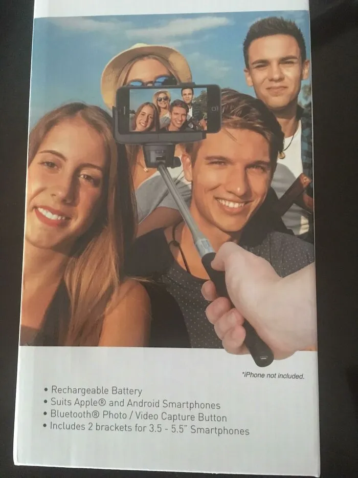 Grupo de personas sonrientes tomando selfie con palo en un fondo que parece un fallo de Photoshop evidente y divertido.