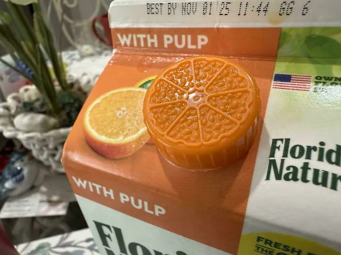 Orange juice carton with a cap designed like an orange slice, showcasing smart and cool product design by designers.