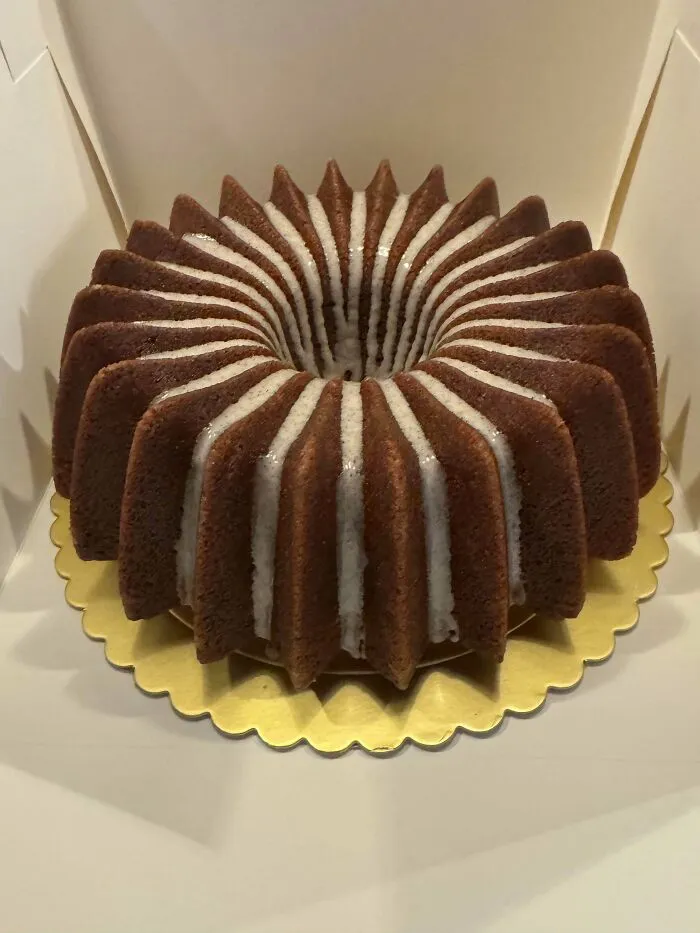 Bundt cake with white glaze drizzled on top, showcasing gorgeous baked goods with intricate design and texture.
