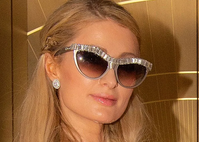 Woman wearing embellished sunglasses and earrings at an event, related to ran into celebrities and wild experiences.
