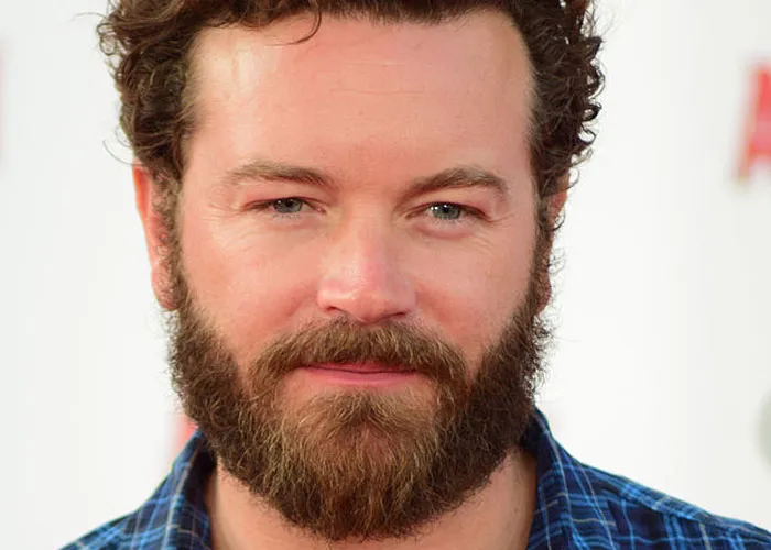 Bearded man in a blue plaid shirt smiling at a celebrity encounter event, capturing a total gentleman vibe.